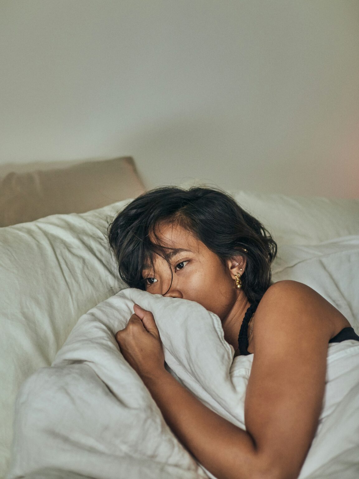 A young woman in bed with period or pregnancy symptoms